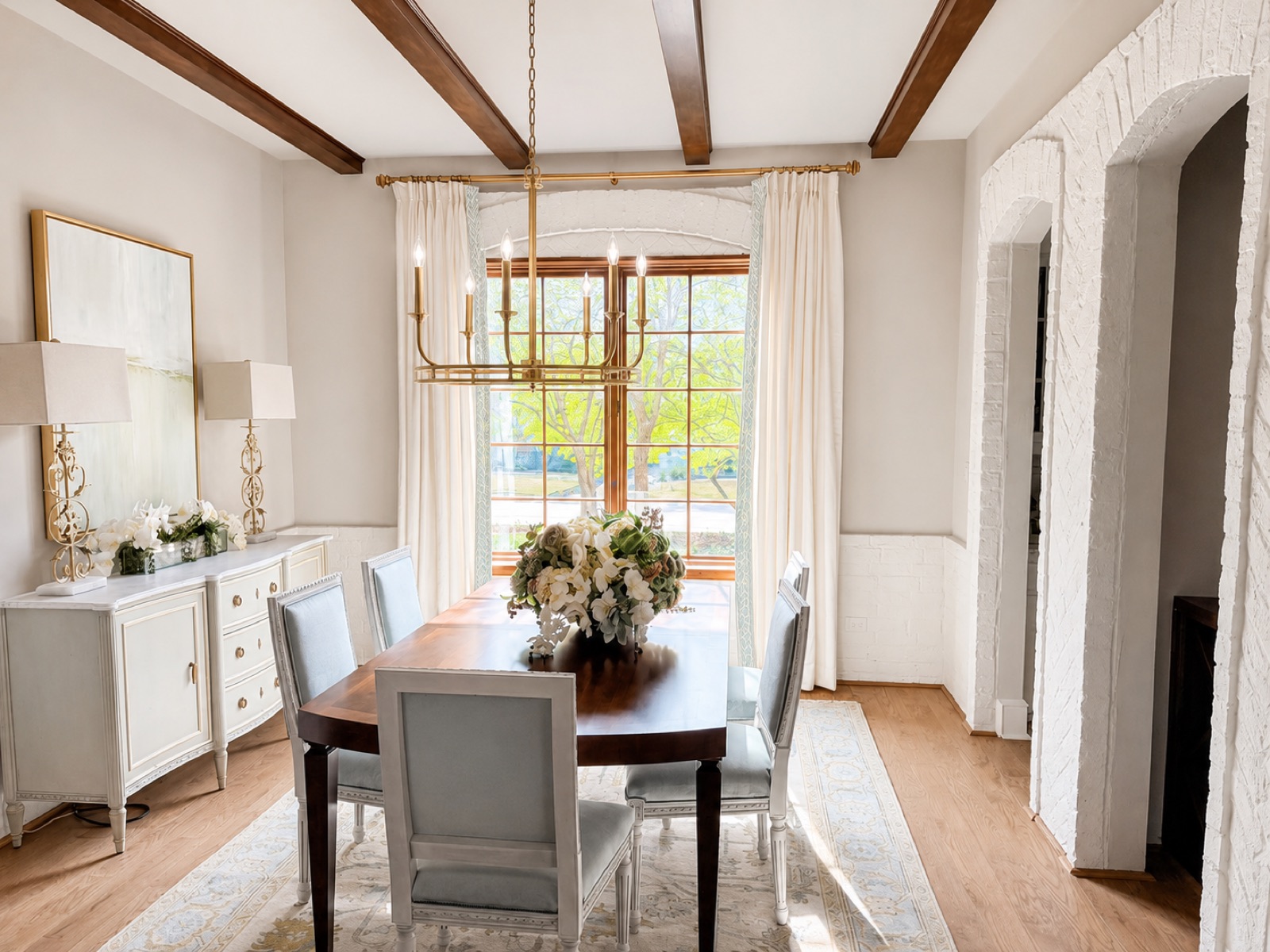 Dining room with wood ceiling beams, brass chandelier, and upholstered chairs