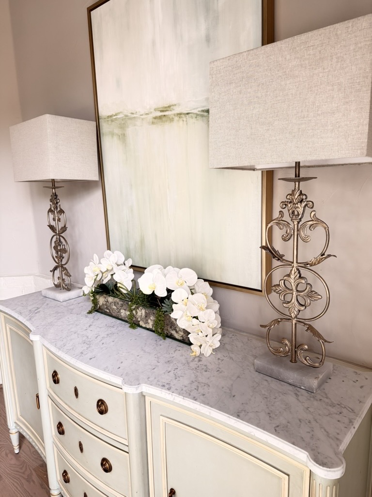Styled sideboard with sculptural lamps, white orchids, and soft abstract artwork