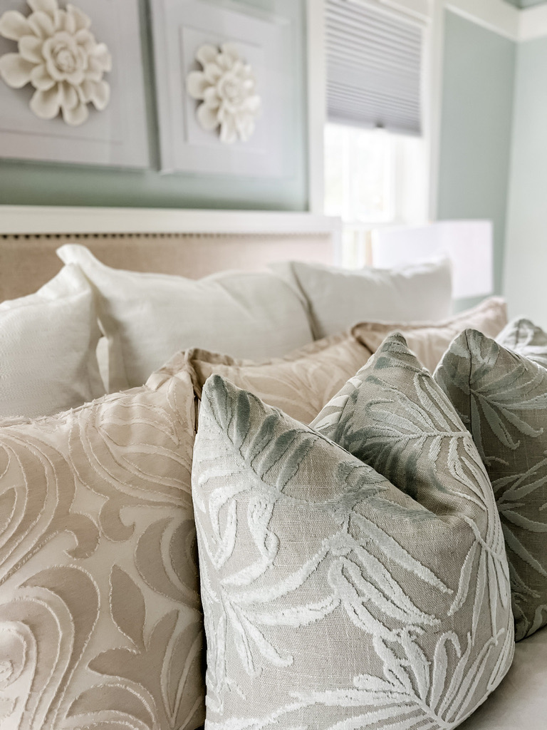 Layered bedding with sage and cream embroidered pillows